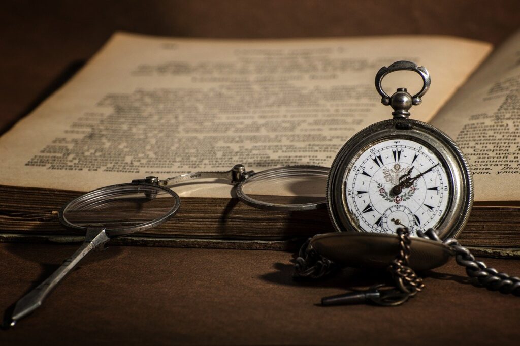 Stary zegarek i okulary przy starodawnej książce