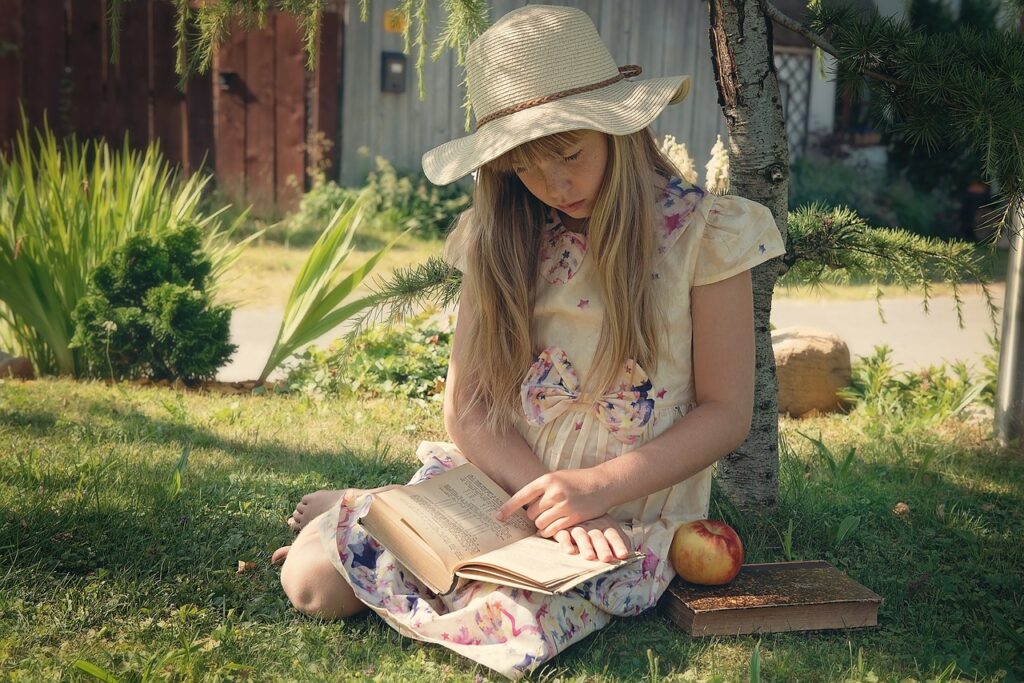 Dziewczynka czyta książkę w ogrodzie